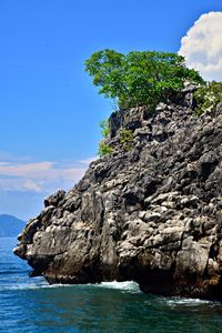 Rock formation by sea against blue sky