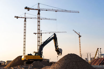 Cranes at construction site against sky