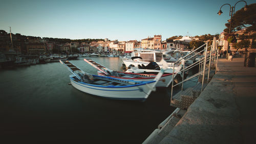 Boats moored at harbor against clear sky