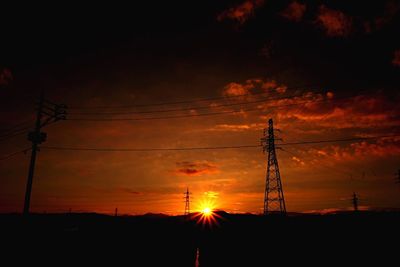 Low angle view of silhouette electricity pylon against sky during sunset