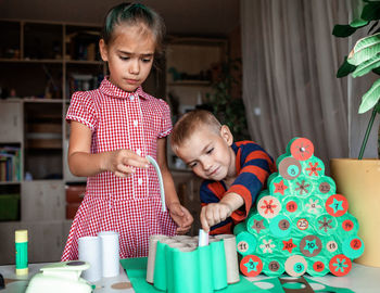 Cute girl and boy preparing christmas decoration at home