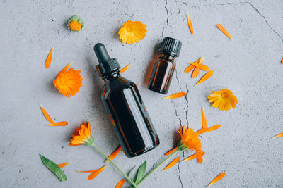 Top view of glass bottles of calendula essential oil with fresh marigold orange 