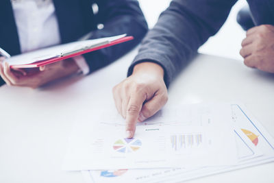 Close-up of businessman and colleague working over graph on table