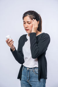 Young woman looking away while standing against white background