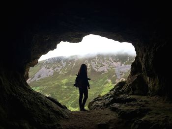 Full length of woman with camera standing in cave