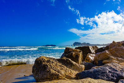 Rocks on beach against blue sky