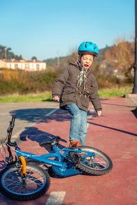 Screaming boy kicking bicycle on road in city during sunny day