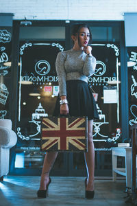 Full length of young woman holding briefcase while standing in store