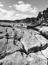 Scenic view of rocks on shore against sky