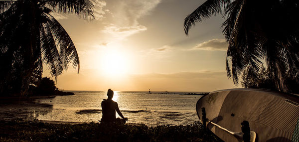 Silhouette man on beach against sky during sunset