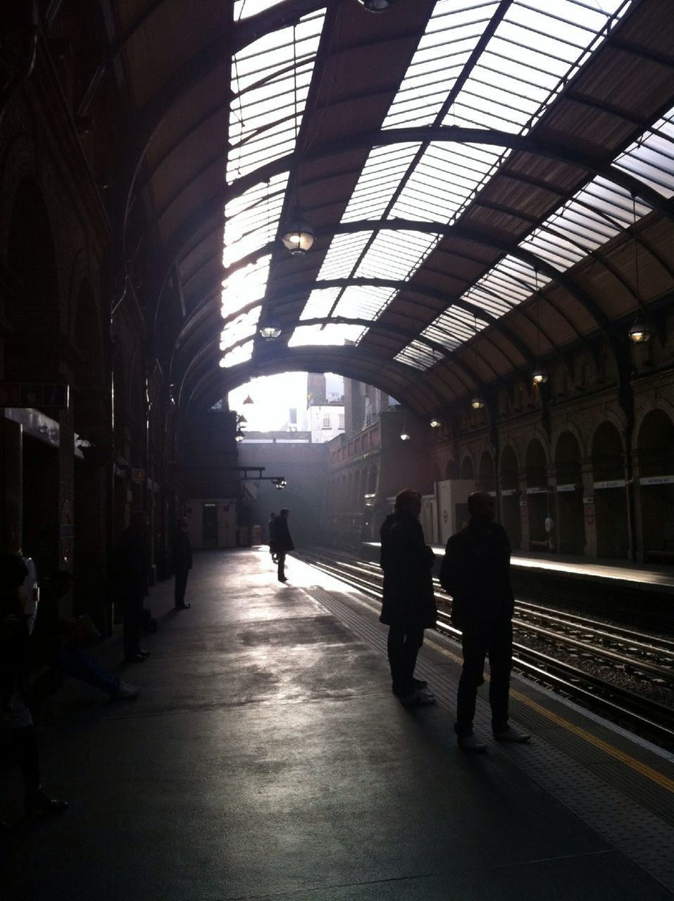 indoors, railroad station, railroad station platform, men, walking, transportation, architecture, public transportation, built structure, lifestyles, ceiling, rail transportation, person, railroad track, full length, illuminated, subway station, travel, passenger