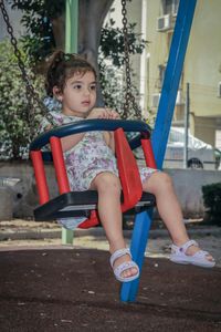 Girl sitting on swing at playground