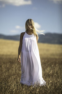 Young woman standing on land against sky