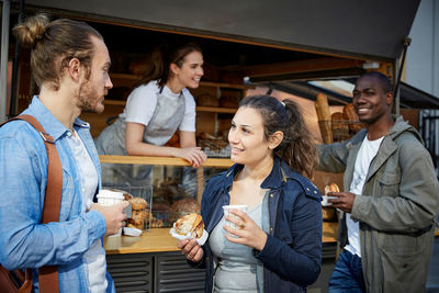 Friends talking while having food and coffee by concession stand