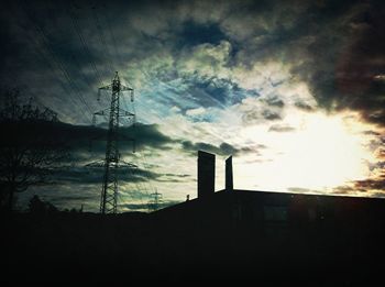 Low angle view of electricity pylon against cloudy sky