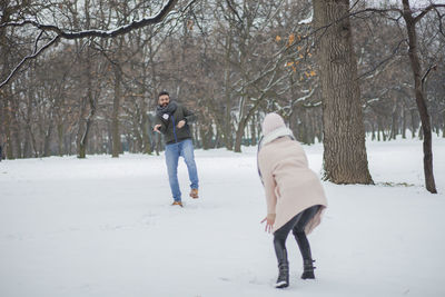 Happy couple playing on snow covered land during winter