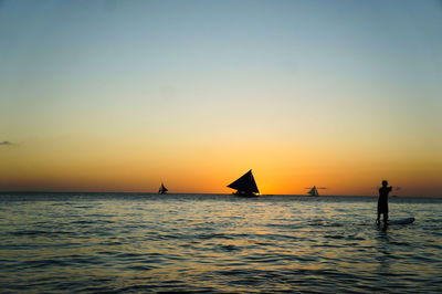 Silhouette sailboat in sea against sky during sunset