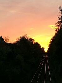 Silhouette railroad tracks against sky during sunset
