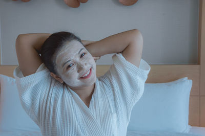 Portrait of young woman lying on bed at home