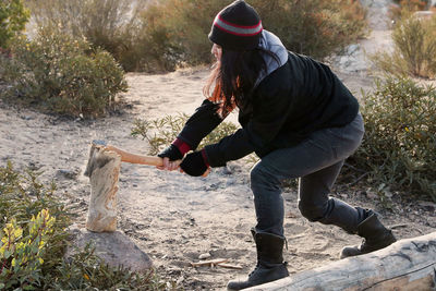 Women chopping wood with axe in desert