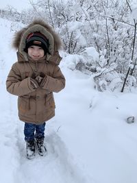 Boy standing on snow covered field during winter