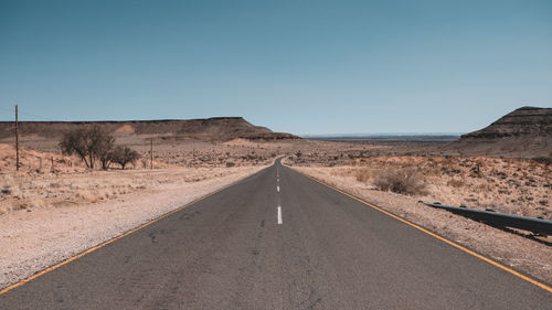 Road amidst desert against clear sky