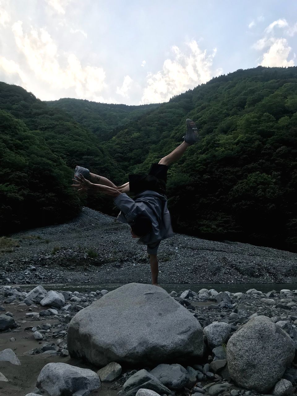 MAN STANDING ON ROCKS AGAINST SKY