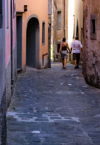 Rear view of people walking on sidewalk in city