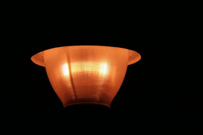 Low angle view of illuminated light bulb against black background