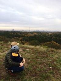 Man sitting on field against sky