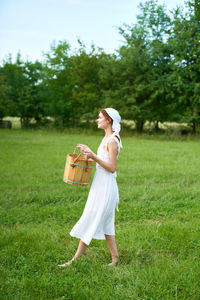 Full length of woman standing in basket on field