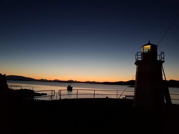 Silhouette tower by sea against sky during sunset