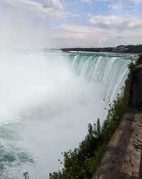 Scenic view of waterfall against sky