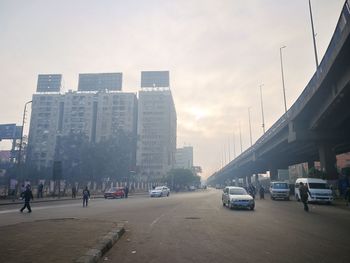 Cars on road in city against sky