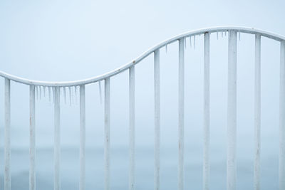 Low angle view of railing against sky during winter