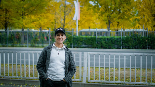 Portrait of young man standing against railing