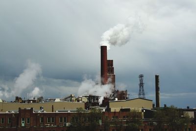 Smoke emitting from factory against sky