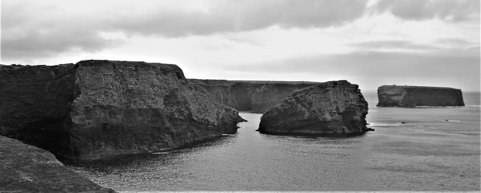 Rock formations by sea against sky