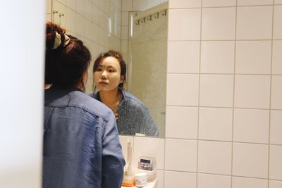 Young woman looking away while standing in bathroom