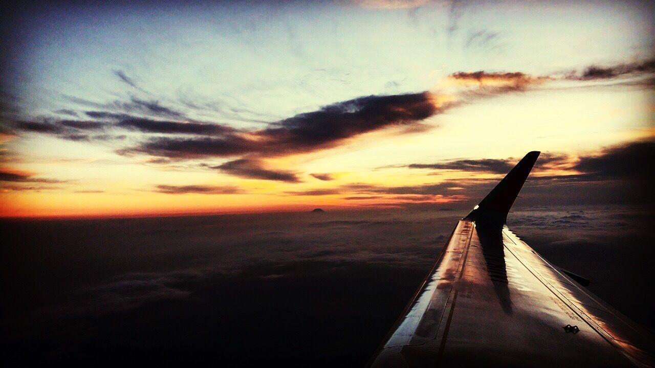 AIRPLANE FLYING OVER SEA AT SUNSET