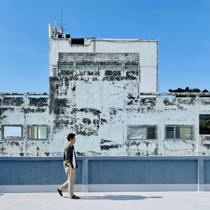 Side view of man standing against building