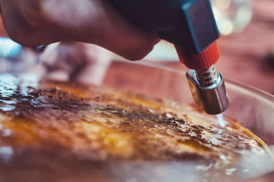 Close-up of hand holding flambe above creme brulee