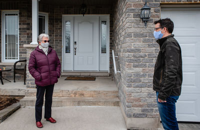 Man and older woman talking while wearing face masks during covid 19.