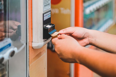 Close-up of hands collecting paper currency dispensing from machine