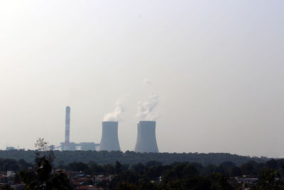Smoke emitting from factory against clear sky