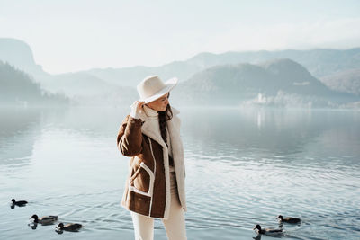 Rear view of woman standing by lake