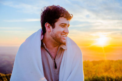 Smiling man in warm clothing against sky during sunset