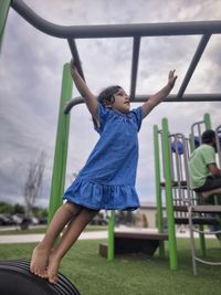 Full length of a girl playing on seat against sky