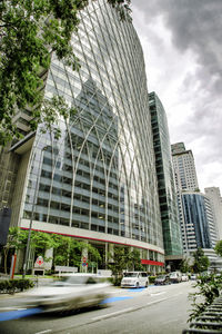 Street by modern buildings against sky in city