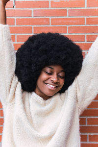 Portrait of young woman standing against brick wall